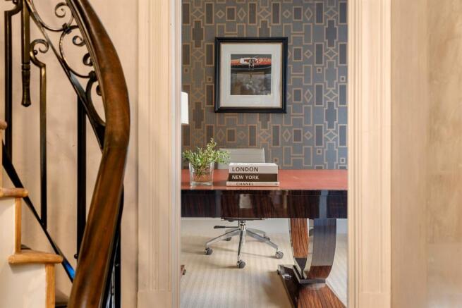 Study with dark wood desk beside the staircase